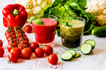 Fresh tomato juice and green detox smoothie in two glasses on a white wooden background