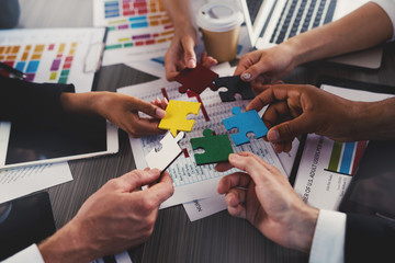 Businessmen building colored puzzles together. Concept of teamwork, partnership, integration and startup