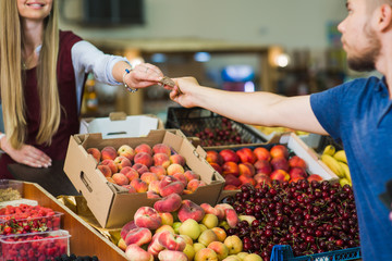 Young man paying cash at food market. Cash payment in close-up. Man pays in cash the seller of vegetables on the market.