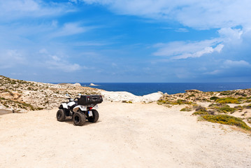Fototapeta premium Quad parked on the beautiful coast of Milos island near the Sarakiniko Beach, Cyclades, Greece.