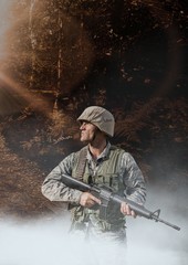 Soldier man holding a weapon against woods