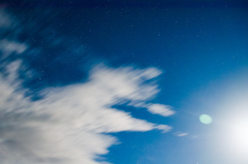 Clouds float in the night sky under moonlight