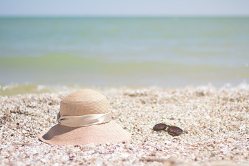 Fototapeta na wymiar A close-up of shells, a straw hat, glasses that lie on the sea, in the distance you can see the sea