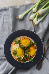 Fried eggs on the plate with cherry tomatoes, spices and green onions in rustic style, top view. Nutritious organic breakfast, healthy lifestyle