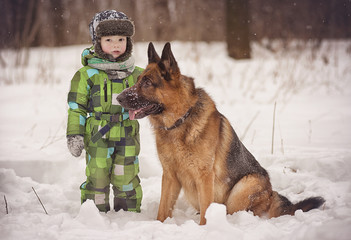 A little boy and a German shepherd in a Park in winter
