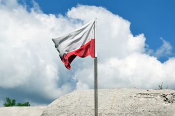 Flaga Polski. Masz przed zabytkowym bunkrem z czasów II Wojny Światowej