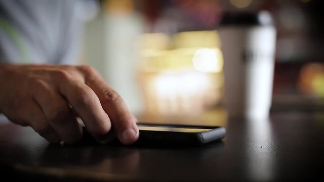 Man's Hand Picking Up Smartphone in Coffee Shop &ndash; Close-Up