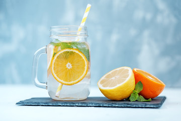 Fototapeta na wymiar Detox water in a glass jar. Lemon and orange and mint. Tasty drink. The concept is summer, diet, vegetarian, fitness, healthy eating and lifestyle.