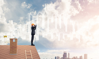 Engineer man standing on roof and looking in binoculars. Mixed m