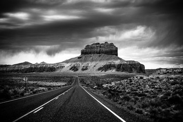 A long straight road through the Utah rocky desert with Storm coming upon a mountain, Goblin Valley State Park, black and white