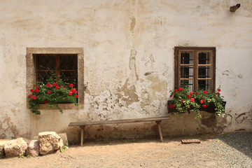 two windows with flowers and bench