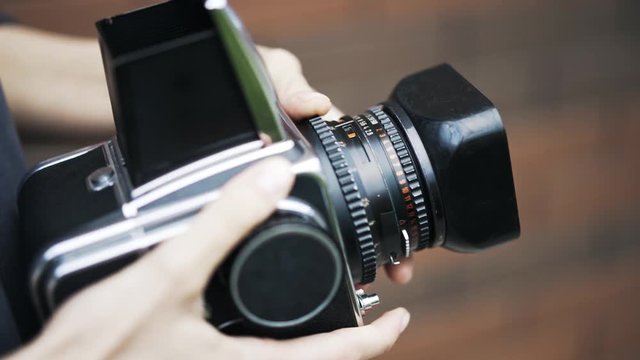 Young woman with an old fashioned camera is making a photo of a young couple. A guy is wearing glasses and hugging his lovely girlfriend. Handheld real time close up shot