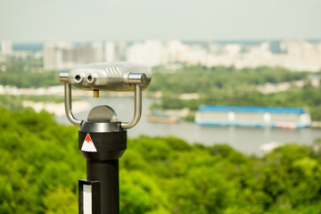 Stationary observation binoculars , metropolis landscape on the background with bridge, river,...
