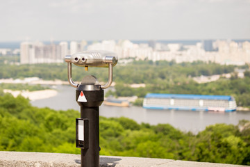 Stationary observation binoculars , metropolis landscape on the background with bridge, river,...