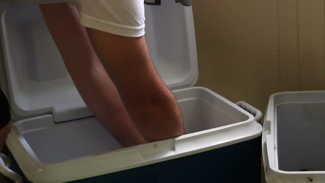 College Student grabs two beers from a ice cooler for a party