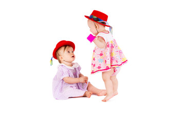 Two lovely babes in colored dresses and red hats are playing on a white background