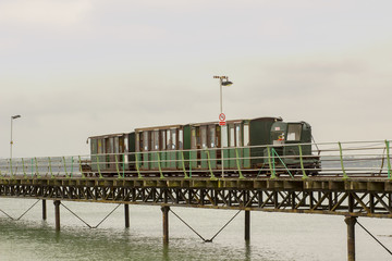 The narrow gauge electric train that runs the length of the Hythe Pier carrying passengers to and from the ferry boat to Southampton taken on a dull wet summer's day.