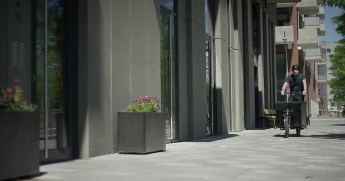 Arrival of a bicycle courier with his modern transportation bike in front of a modern building