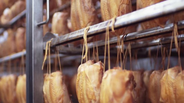 Close up view of the chickens being smoked in the automatic china smoking machine. Junk food, tasty products. Manufacturing equipment, delicious traditions. Workplace, bread-baking business.