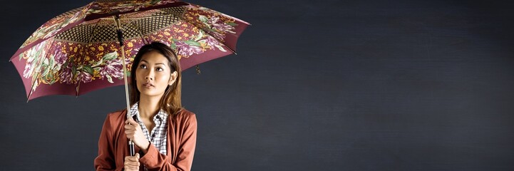 Millennial woman with patterned umbrella against navy chalkboard