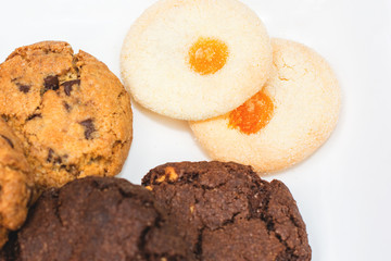 Top view of a plate of oatmeal chocolate, shortbread cookies on a white background