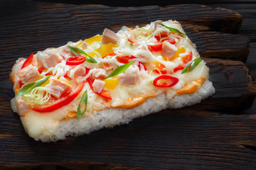 Piece of appetizing rice pizza with bacon served on rustic wooden table.Delicious asian food