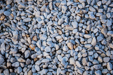 The background with brown, yellow and grey small angular stones of different sizes and shapes with rough surface and inclusions of another colors. Flat view