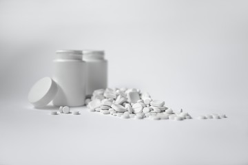 White pills on white background, bottle