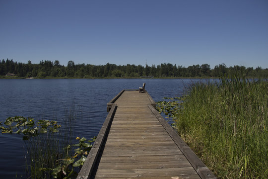 Wooden dock with a lone bench reaching into Lake Cassidy near Lake Stevens, Washington