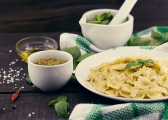  Farfalle pasta with pesto genovese (basil sauce) on rustic wooden table. Italian cuisine