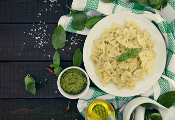  Farfalle pasta with pesto genovese (basil sauce) on rustic wooden table. Italian cuisine.  Flat lay. Top view.