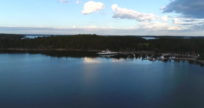 Mossala ferry, Cinema 4k aerial view towards a white ferry, docked at a terminal, heading to inio, on a sunny summer evening, in houtskari, in the finnish archipelago of Turku