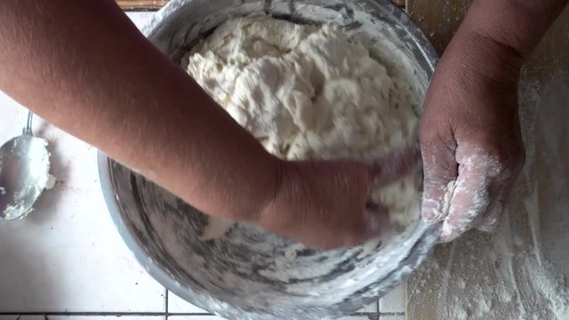 Mixing the dough in a metal bowl. Kneading dough. UHD real time footage