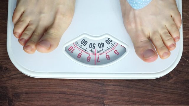 Female feet stepping on bathroom scales. Woman standing on weighing machine. Health care, weight loss concept. 4K ProRes HQ codec