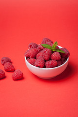 Bowl with fresh raspberries on a red background. Minimal concept. Copy space