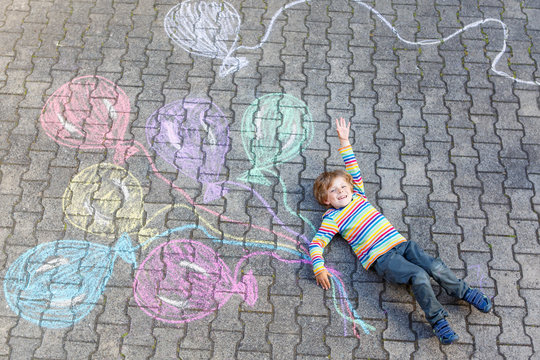 Kid boy having fun with colorful balloons drawing with chalks