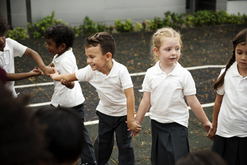 Group of diverse kindergarten students standing holding hands together