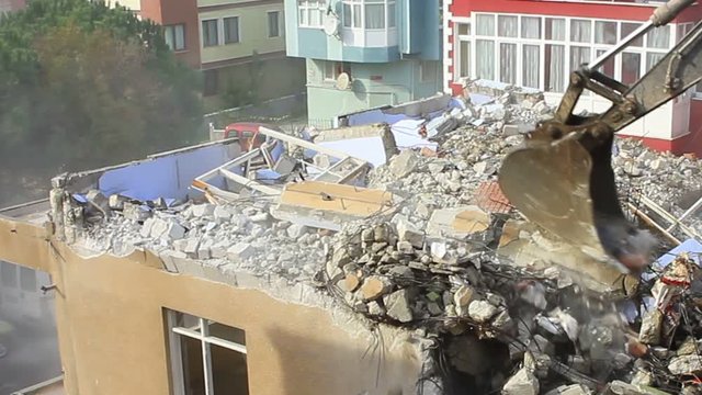 Demolition of building with concrete floors and pillars on construction site. Crawler dozer turning homes into rubble