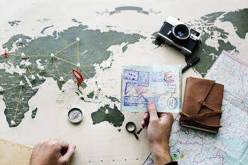 Aerial view of hand holding passport planning the journey with the map