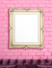 Blank golden vintage victorian style picture frame hanging on pink brick wall over luxury purple sofa,Mock up for display or montage of product or text,vertical proportion