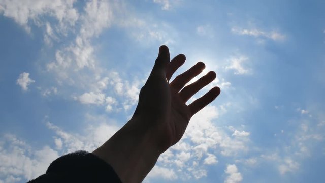 Hand of man strive to sun into the deep blue sky. Conceptual scene.