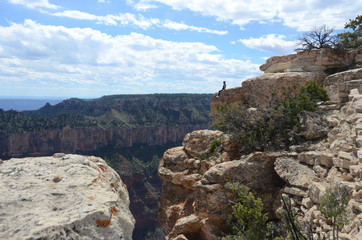 blue cloudy sky and canyon wall in background cliff with person in foreground