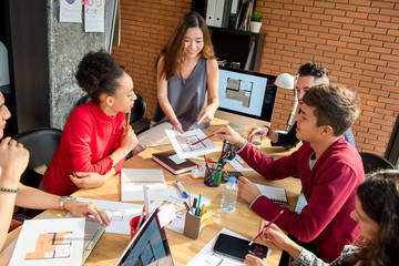 Casual Asian businesswoman sitting on the table presenting work to her colleagues in the meeting