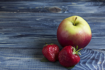 Apple and strawberry on a wooden table. Fruit still life.