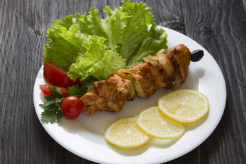 Chicken skewers with vegetables on a white plate. Still life in rustic style. Dish on a wooden table.