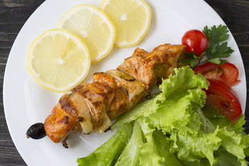 Chicken skewers with vegetables on a white plate. Still life in rustic style. Dish on a wooden table.