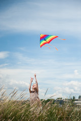 beautiful little girl holding flying kite in the field on summer sunny day