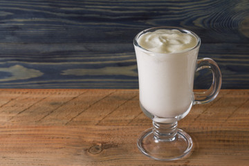 A glass with an eggnog on a wooden table