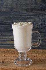 A glass with an eggnog on a wooden table