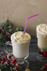 Two glasses of eggnog on a wooden table. Christmas time.